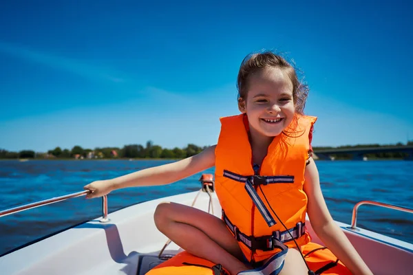 Gadis kecil dengan rompi renang duduk di perahu motor Stok Foto Bebas Royalti