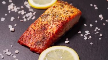 Mutfaktaki siyah tabakta lezzetli pişmiş altın somon balığı.