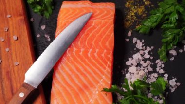 Siyah taş bir masada tuzlu ve baharatlı taze somon.