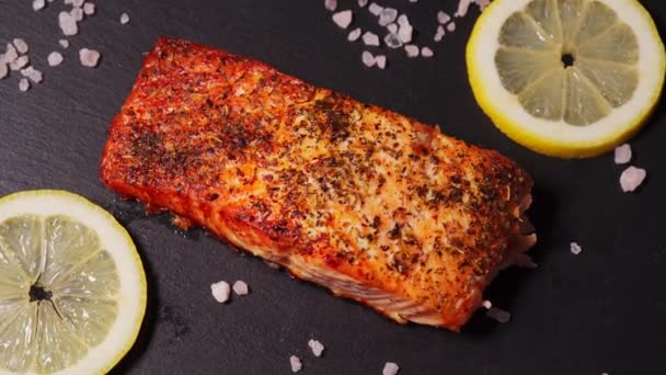 Delicioso salmón dorado al horno en un plato negro en la cocina — Vídeo de stock