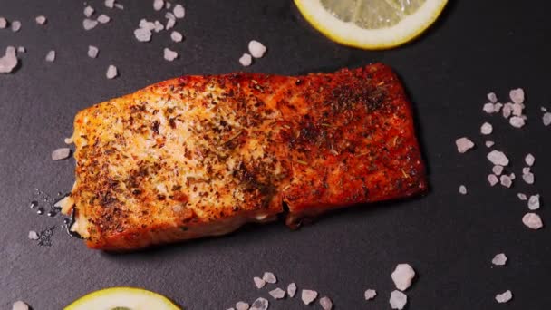 Köstlicher gebackener goldener Lachs auf einem schwarzen Teller in der Küche — Stockvideo