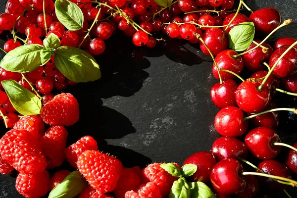 Delicious and juicy red raspberries and cherries on a black table — Stock Photo, Image