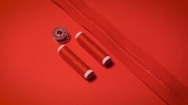 Kırmızı minimalist arkaplanda iplikler ve fermuar