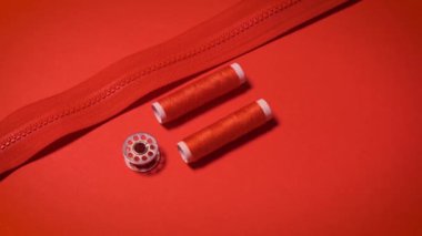 Kırmızı minimalist arkaplanda iplikler ve fermuar