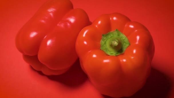 Saftig glänzender Paprika auf rotem Hintergrund — Stockvideo