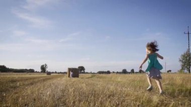 İki küçük tatlı kız yazın bir tarlada çavdar ekmeği itiyor.