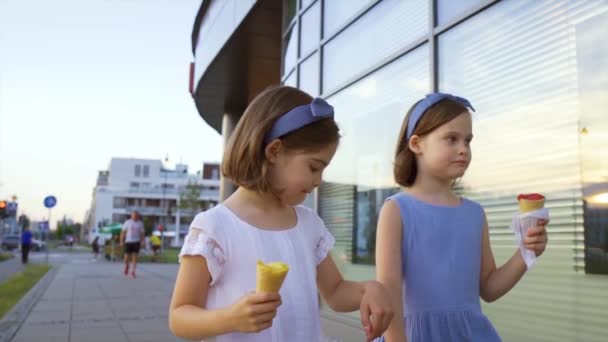 Dwie słodkie dziewczynki spacerują po mieście i jedzą lody — Wideo stockowe