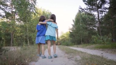 İki tatlı kız orman yolunda yürüyor ve konuşuyorlar.