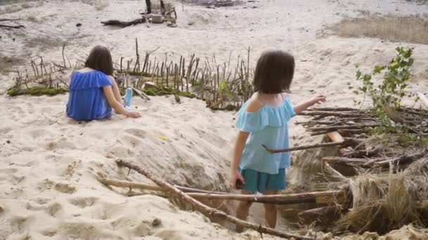 カラフルなドレスを着た2人の女の子が森の砂の上で遊んでいます — ストック動画