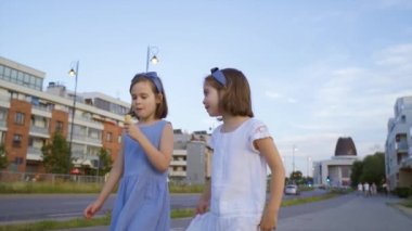 İki küçük tatlı kız şehirde dolaşıp dondurma yiyorlar.