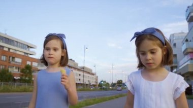 İki küçük tatlı kız şehirde dolaşıp dondurma yiyorlar.