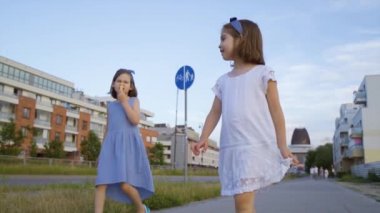 İki küçük tatlı kız şehirde dolaşıp dondurma yiyorlar.