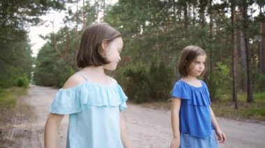 İki tatlı kız orman yolunda yürüyor ve konuşuyorlar.