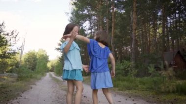 İki tatlı kız orman yolunda yürüyor ve konuşuyorlar.