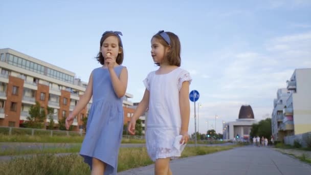 两个可爱的小女孩在城里走来走去，吃着冰激凌 — 图库视频影像