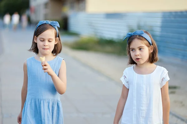 İki küçük tatlı kız şehirde dolaşıp dondurma yiyorlar. — Stok fotoğraf