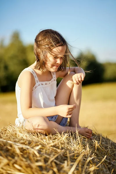 Cute little girl siedzi na żyto kosić w polu — Zdjęcie stockowe