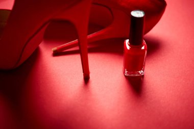 Kırmızı yüksek topuklu ayakkabılar ve minimalist bir arka planda oje.