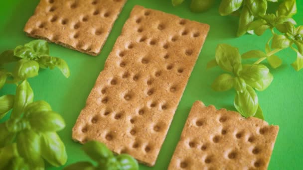 Delizioso e croccante pane dietetico e basilico su un tavolo verde — Video Stock