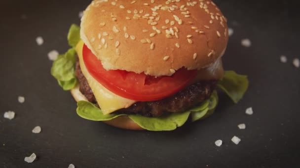 Finom sajtburger egy fekete asztalon, sós kristályokkal — Stock videók