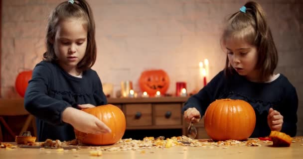 Dwie słodkie dziewczynki są cięcia dyni na stole na Halloween — Wideo stockowe