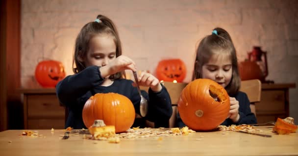 Dwie słodkie dziewczynki są cięcia dyni na stole na Halloween — Wideo stockowe