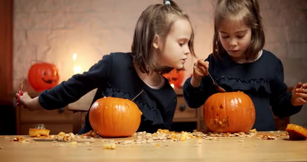 Dwie słodkie dziewczynki są cięcia dyni na stole na Halloween — Wideo stockowe