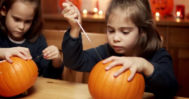 dvě roztomilé holčičky krájí dýni na stole na Halloween