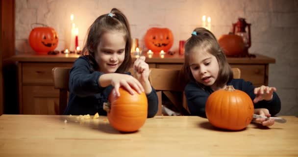 Zwei süße kleine Mädchen schneiden zu Halloween einen Kürbis auf den Tisch — Stockvideo