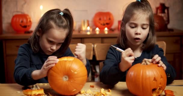 Dwie słodkie dziewczynki są cięcia dyni na stole na Halloween — Wideo stockowe