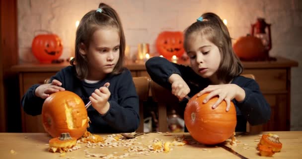 Twee schattige kleine meisjes snijden een pompoen op de tafel voor halloween — Stockvideo