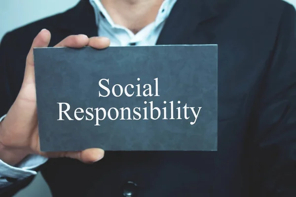 Businessman showing Social Responsibility word on cardboard.