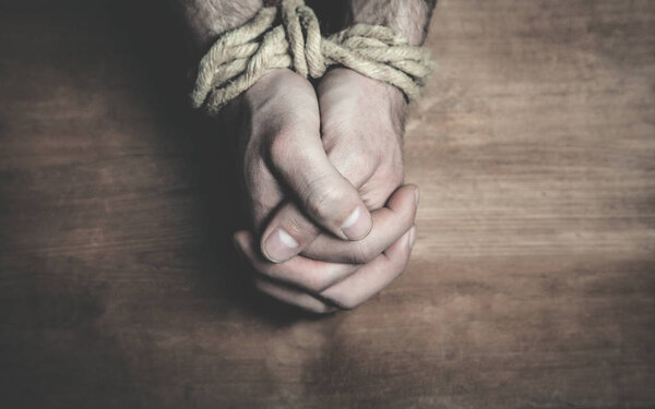 Male hands tied with a rope.