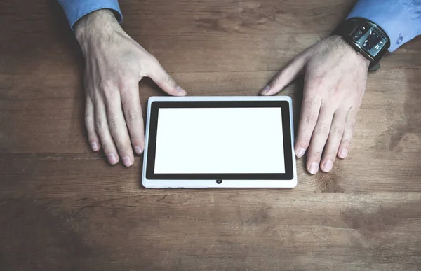 Tablet beyaz ekran görüntüsünü ahşap masanın üzerinde kullanarak eller.