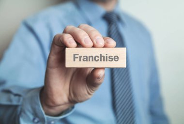 Franchise kelime ahşap blok içinde gösteren işadamı.