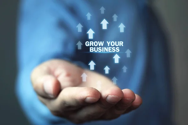 Man holding Grow Your Business words with growth arrows.