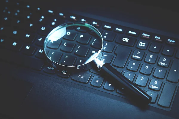 Laptop klavye üzerinde büyüteç. İnternet üzerinde arama