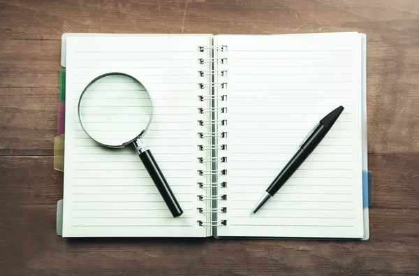 Büyüteç ve Not defteri üzerinde kalem. İş kavramı