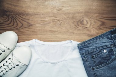 Beyaz spor ayakkabı kot pantolon ve gömlek ahşap arka plan üzerinde.