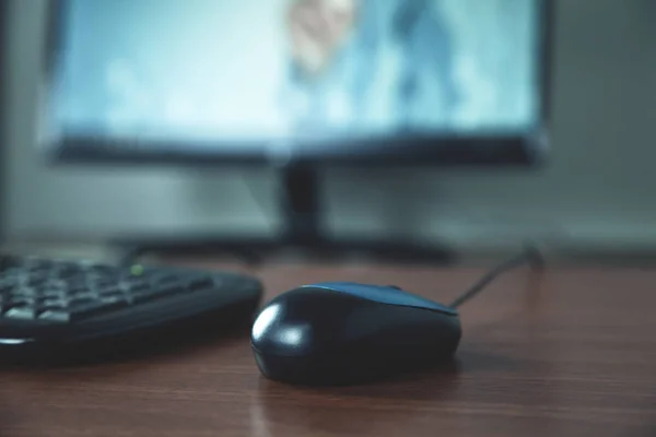 Close up computer mouse, keyboard and monitor on wooden table.