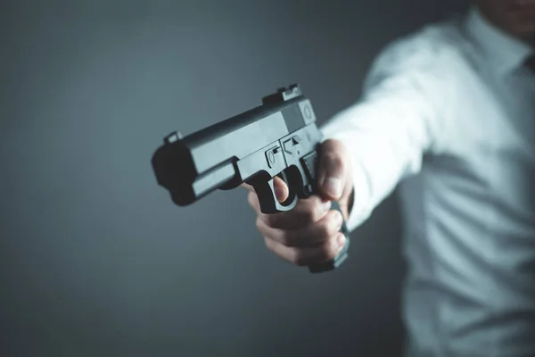 Beyaz adam ayakta ve silahla nişan.