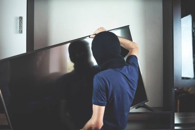 Hırsız ile siyah yün modern pahalı televizyon çalmak.