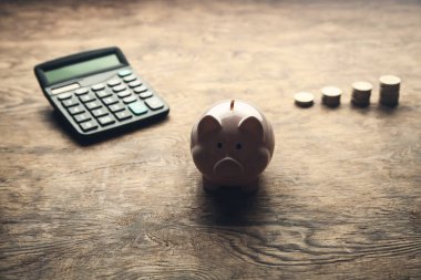 Sikke ve ahşap masa hesap makinesi yığını ile Piggy banka. Paranı sakla