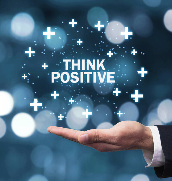 Man hand holding Think Positive words with plus signs.