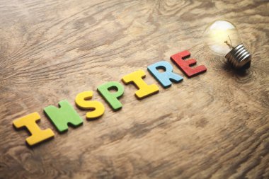 Renkli word esin ve ampul ahşap masa üzerinde. İlham ve yaratıcılık