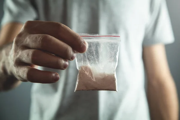 コカインの粉末をプラスチックのパケットを保持している麻薬の売人 — ストック写真