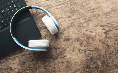 Ahşap arka plan üstünde laptop ile kulaklıklar.