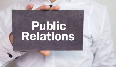 Halkla ilişkiler kelime karton üzerinde gösteren işadamı.