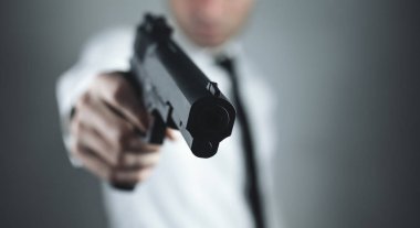 Beyaz adam ayakta ve silahla nişan.