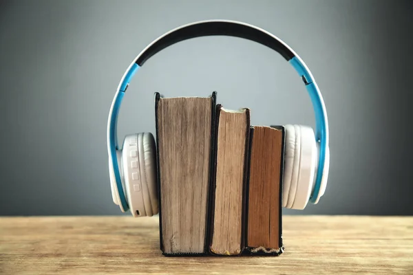 Headphones and books on wooden table. Audio book concept